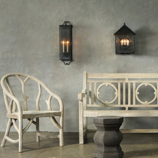 LUMENS LAMP Giatti 中型户外壁灯，采用午夜黑锻铁饰面和透明种子玻璃，安装在灰色纹理墙面上方。